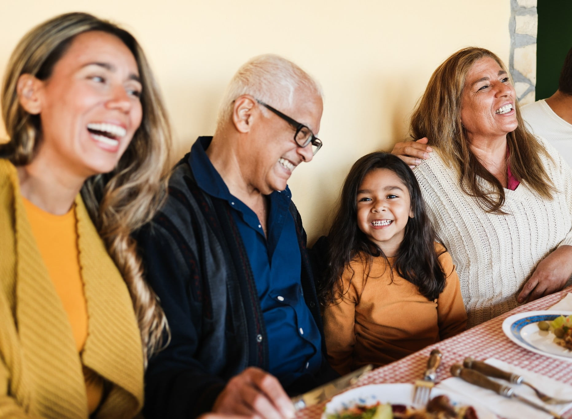 A family all sitting at a dinner table laughing and enjoying dinner together.