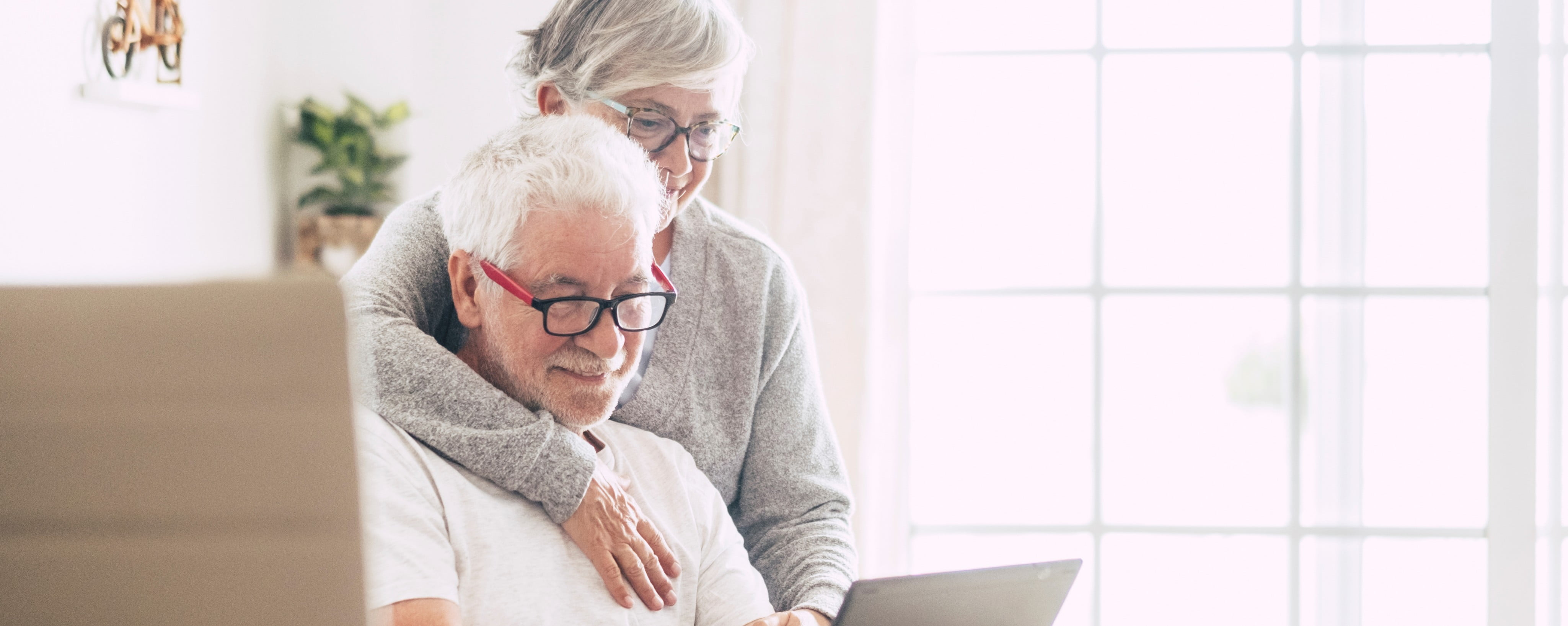 an elderly couple with the man on a laptop.