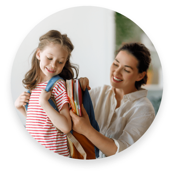 A picture of a little girl getting help with her backpack
